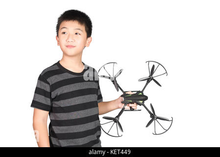 Asiatischer Junge mit Hexacopter-Drohne oder Quadrocopter-Spielzeug in der Hand, Studioaufnahme isoliert auf weißem Hintergrund. Stockfoto