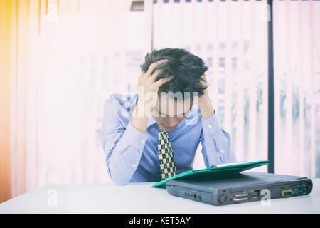 Asian Business Mann ernsthaft an die Arbeit, bis die Kopfschmerzen, Soft Focus getan Stockfoto