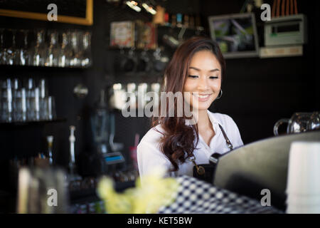 Asiatische Frauen barista lächelnd und mit Kaffeemaschine im Coffee Shop counter-Working Woman Small Business Owner Essen und Trinken cafe Konzept Stockfoto