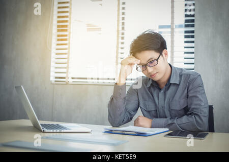 Asiatische Geschäftsleute ernsthaft an die Arbeit, bis die Kopfschmerzen geleistet und Notebook und Document auf Tisch Stockfoto