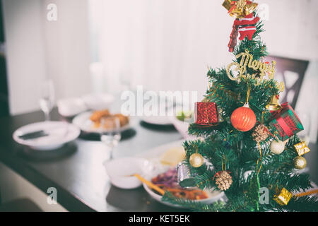 Weihnachtsbaum am Tisch zum Abendessen mit Huhn in der Nähe von Stockfoto