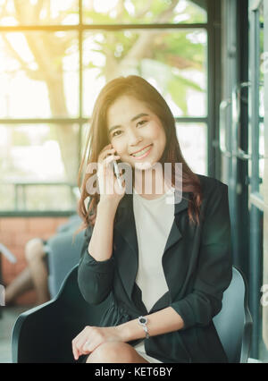 Geschäftsmänner und Frauen sind mit Handy und Smartphone für Kommunikation und Kontrolle über die Menschen in Büro Background, Soft Focus Stockfoto