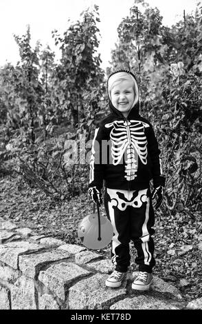 Trick oder Festlichkeit. glückliches Kind tragen Skelett Kostüm für Halloween im Freien holding Kürbis Jack o'Lantern Warenkorb Stockfoto