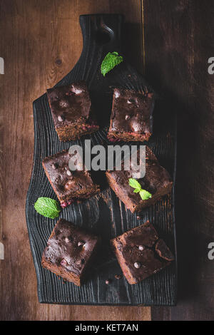 Dark chocolate Brownies mit minzeblatt auf dunklem Hintergrund eingerichtet. top Aussicht, vertikalen Zusammensetzung Stockfoto