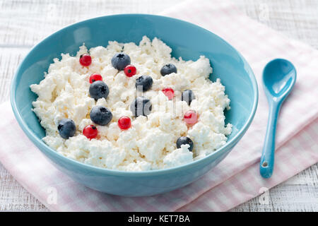 Frische Landwirt Käse, Quark, Ricotta oder Tvorog mit frischen Beeren in blauer Schüssel. gesunde organische Milch und Milchprodukten Stockfoto