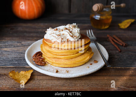 Kürbis Pfannkuchen mit Sahne und Zimt auf alten Holztisch. Herbst Komfort Essen, Frühstück essen Stockfoto