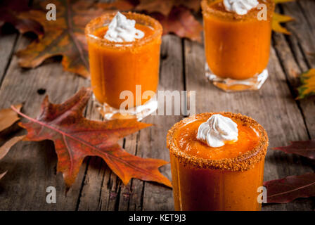 Herbst trinken. Ideen und Rezepte für Danksagung, Halloween. Alkohol cocktail Kürbistorte Wodka Schüsse auf alten rustikalen Holztisch mit Herbstlaub, Co Stockfoto