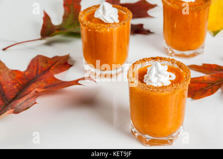 Herbst trinken. Ideen und Rezepte für Danksagung, Halloween. Alkohol cocktail Kürbistorte Wodka Schüsse auf weißem Marmor tisch mit Herbstlaub, Kopieren sp Stockfoto