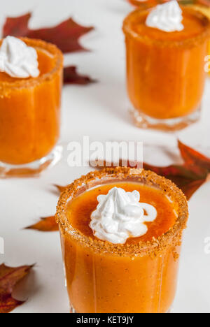 Herbst trinken. Ideen und Rezepte für Danksagung, Halloween. Alkohol cocktail Kürbistorte Wodka Schüsse auf weißem Marmor tisch mit Herbstlaub, Kopieren sp Stockfoto