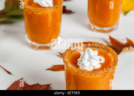 Herbst trinken. Ideen und Rezepte für Danksagung, Halloween. Alkohol cocktail Kürbistorte Wodka Schüsse auf weißem Marmor tisch mit Herbstlaub, Kopieren sp Stockfoto