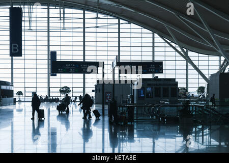 Shanghai, China - Dezember 6, 2014: Passagiere im Wartesaal von Shanghai Pudong International Airport. Zurück beleuchteten Foto mit dunklen Silhouetten Stockfoto