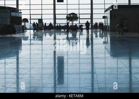 Shanghai, China - Dezember 6, 2014: Passagiere Spaziergang in einer Wartehalle von Shanghai Pudong International Airport. Zurück beleuchteten Foto mit dunklen Silhouetten Stockfoto