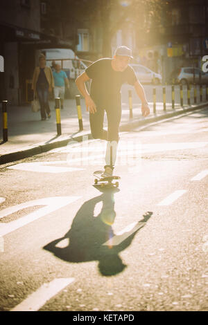 Pro Skate rider ride Skateboard vor dem Auto auf die Stadt Straße Straße durch Staus Stockfoto