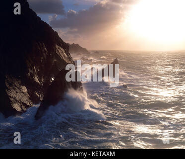 Kanal Inseln. Guernsey. La Corbiere. Wellen, die auf den Klippen bei Sonnenaufgang. Stockfoto
