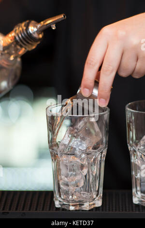 Ein Barkeeper/bar Arbeiter gießt Aufnahmen von Spirituosen in einer Bar Pub. Stockfoto