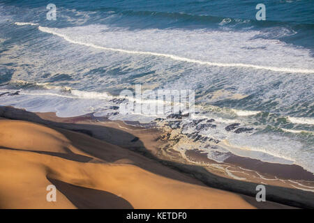 Luftaufnahme von Wellen des Atlantik Krachen gegen die Sanddünen der Wüste Namib Namibia Südafrika Stockfoto