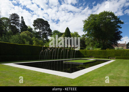 Die zeitgenössische Wasser Garten mit moderner Kunst Skulptur ist von hohen Eibe Hecken umschlossen, Gärten, Cotswolds Kiftsgate Court, Gloucestershire, England. Stockfoto