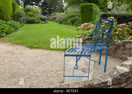 Ein stilvoll geformte schmiedeeisernen Sitz schaut in Richtung der Breite Rand von Kiftsgate Court in der Nähe von Chipping Campden, Cotswolds, Gloucestershire, England. Stockfoto