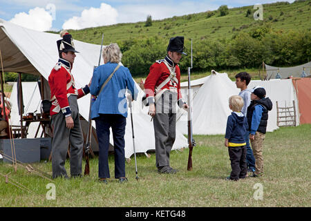 Männer, die als Soldaten gekleidet sind und sich auf einem Geschichtsfest mit Besuchern unterhalten. Stockfoto