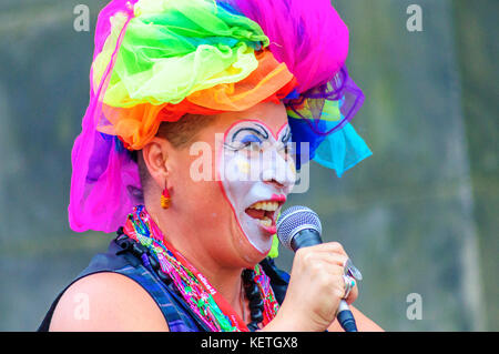 Performerin mit bemaltem Gesicht und trägt eine bunte Kopfbedeckung führt auf der High Street während des Edinburgh Festivals finge Stockfoto