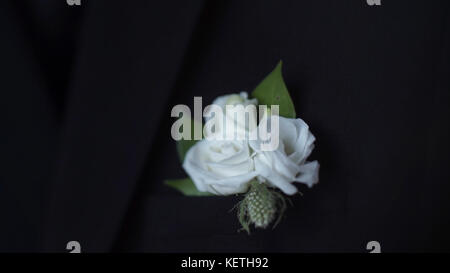 Weiße Blume in seiner Jackentasche Nahaufnahme. Bräutigam Boutonniere passt seine Hand in eine Jackentasche. Stilvoller und klassischer Bräutigam und die Details seines Outfits Stockfoto
