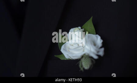 Weiße Blume in seiner Jackentasche Nahaufnahme. Bräutigam Boutonniere passt seine Hand in eine Jackentasche. Stilvoller und klassischer Bräutigam und die Details seines Outfits Stockfoto