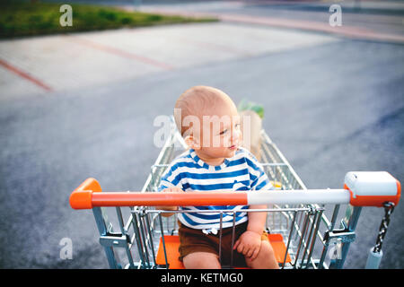 Baby Boy in den Einkaufswagen draussen zu sitzen. Stockfoto