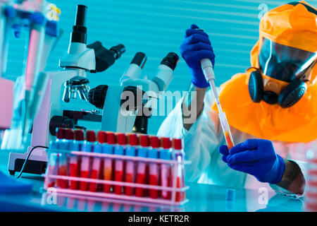 Die Forschung der gefährlichen Viren im Labor. Verhinderung einer Pandemie. Ein Wissenschaftler in einem biologischen Schutzanzug arbeitet mit einer Pipette Stockfoto