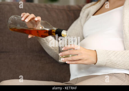 Nahaufnahme eines unverantwortlichen schwangere Frau Alkohol auf der Couch zu Hause sitzen Stockfoto