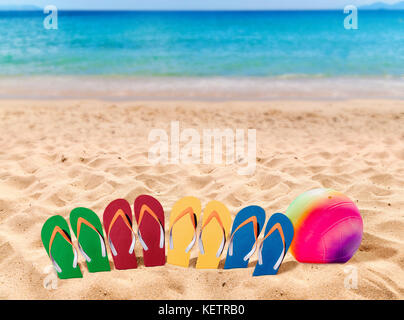 Mann Lebensstil vier Entspannen flip flops auf orange Sand und Volleyball Stockfoto