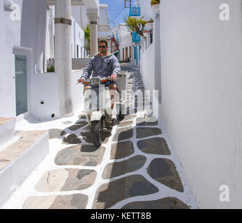 Lokale Mann auf Roller fährt auf eine enge Gasse, Mykonos Stadt, Mykonos, Griechenland Stockfoto