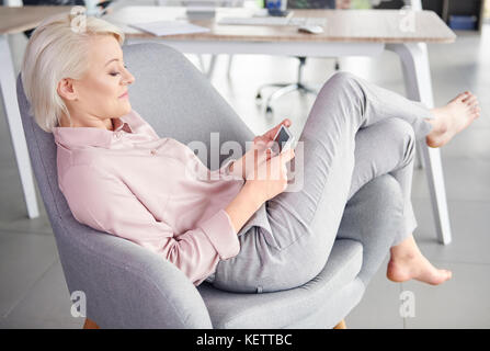 Barfuß Frau mit Handy entspannend Stockfoto
