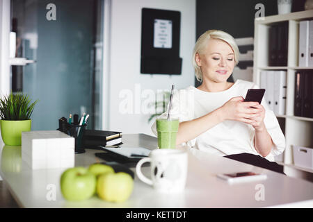 Geschäftsfrau mit einem MOBILEPHONE während der Mittagspause Stockfoto