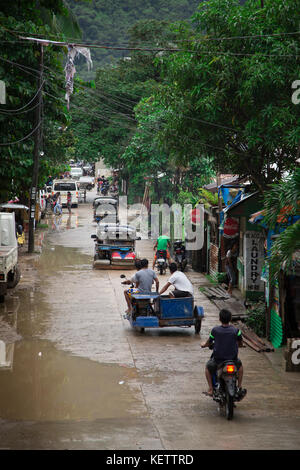 Motorisierte dreiräder (auto Rikscha) und Motorräder in nassen Straßen von El Nido, Palawan, Philippinen Stockfoto