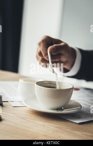 Geschäftsmann Zucker hinzufügen zu Kaffee Stockfoto