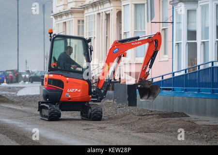 Aberystwyth Wales uk, uk Wetter Montag, 23. Oktober 2017: Nach dem Sturm Winde und wilden Meere der Sturm Brian, lokale Behörde Rat Arbeitnehmer und Auftragnehmer mit Jcb und Bürsten beginnen den Prozess der Clearing die hunderte von Tonnen von Sand und Kies auf die Promenade und das Meer in Aberystwyth gewaschen auf der Cardigan Bay Küste von West Wales. Sie erwarten, dass die Straße für den Verkehr zu haben wieder durch den Nachmittag Foto: Keith Morris/alamy leben Nachrichten Stockfoto