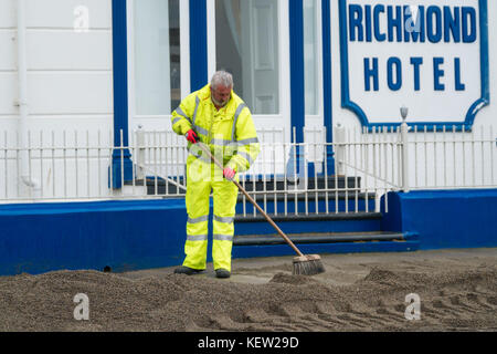 Aberystwyth Wales Vereinigtes Königreich, Montag, 23. Oktober 2017 Vereinigtes Königreich Wetter: Nach dem Sturm Wind und wilde Meere des Sturms Brian, Mitarbeiter des gemeinderats und Auftragnehmer, die JCB's und Bürsten verwenden, beginnen mit der Reinigung der Hunderte Tonnen von Sandsand und Kies, die an der Promenade und am Meer in Aberystwyth an der Küste von Cardigan Bay in westwales angespült wurden. Sie erwarten, dass die Straße bis zum Nachmittag wieder für den Verkehr freigegeben wird. Foto: Keith Morris/Alamy Live News Stockfoto