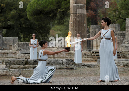 Olympia, Griechenland. Oktober 2017. Die griechische Schauspielerin Katerina Lehou (R) zündet die olympische Fackel in Olympia, Griechenland, 24. Oktober 2017 an. Die südkoreanische Stadt Pyeongchang ist Austragungsort der Olympischen Winterspiele 2018. Quelle: ALKIS Konstantinidis/POOL/dpa/Alamy Live News Stockfoto