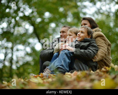 Glücklich lächelnde Familie sitzt auf den Blättern