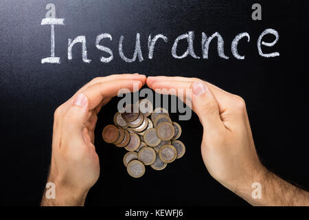 Person schützende Hand Münzen Übersicht Versicherungen Konzept auf der Tafel Stockfoto