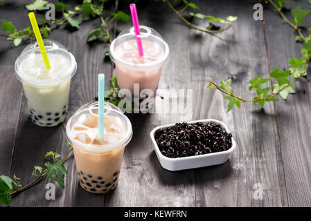 Vielzahl von Bubble Tea in Plastik Becher mit Pailletten auf einem Holztisch. Stockfoto