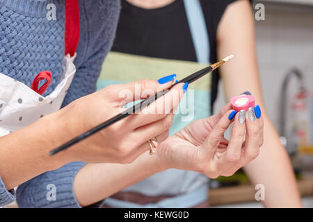 Close-up Frau Konditor malt auf eine Süßigkeit in Form eines Herzen Stockfoto