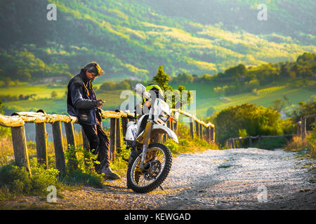 Auf einer off road motocross Track ein Biker Rest am Sonnenuntergang auf einem hölzernen Zaun in der Colli Euganei, Italien, 22. April 2017 Stockfoto