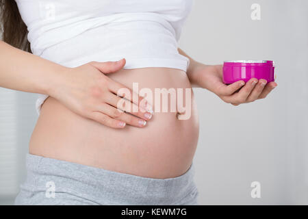 In der Nähe der schwangeren Frau, die Sahne auf den Bauch Stockfoto