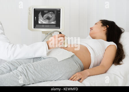 Männlicher Arzt Durchführung Ultraschall auf erwartet Frau in Klinik Scan Stockfoto