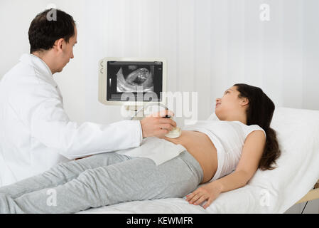 Männlicher Arzt Durchführung Ultraschall auf erwartet Frau in Klinik Scan Stockfoto