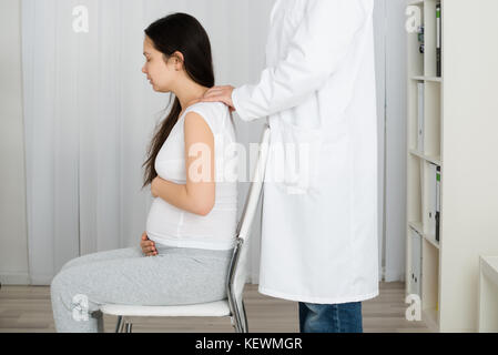 Mann massieren schwangere Frau auf Stuhl Stockfoto