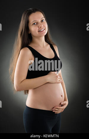 Portrait von schöne schwangere Frau auf schwarzem Hintergrund Stockfoto
