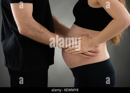 Den mittleren Abschnitt des jungen Mannes berühren schwangeren Bauch Stockfoto