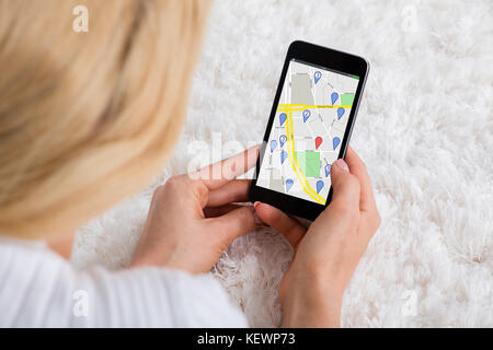 Nahaufnahme einer Frau liegend auf dem Teppich mit GPS Navigation Karte am Handy Stockfoto